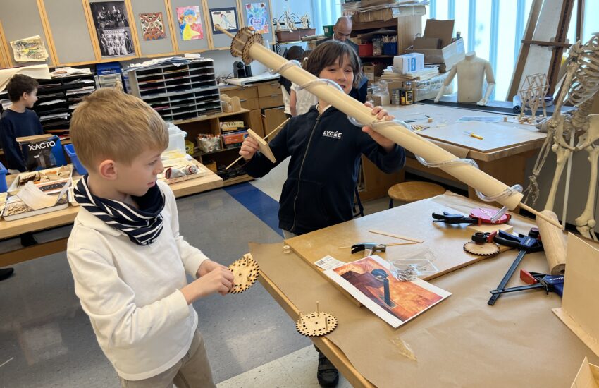 Fourth graders work at an art table to rebuild on of Leonardo Da Vinci's inventions.