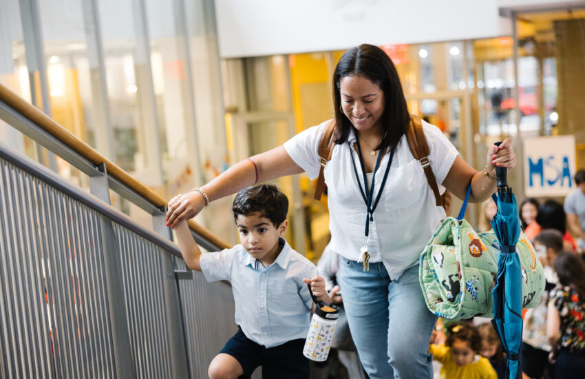 Mother and son walk up a staircase of a school to head to a classroom.