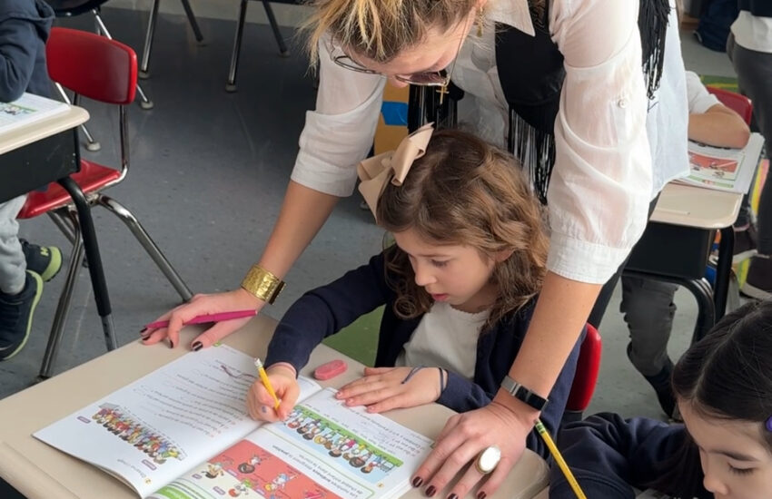 Teacher and young student work on math textbook